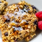 oatmeal in a white plate next to raspberries.