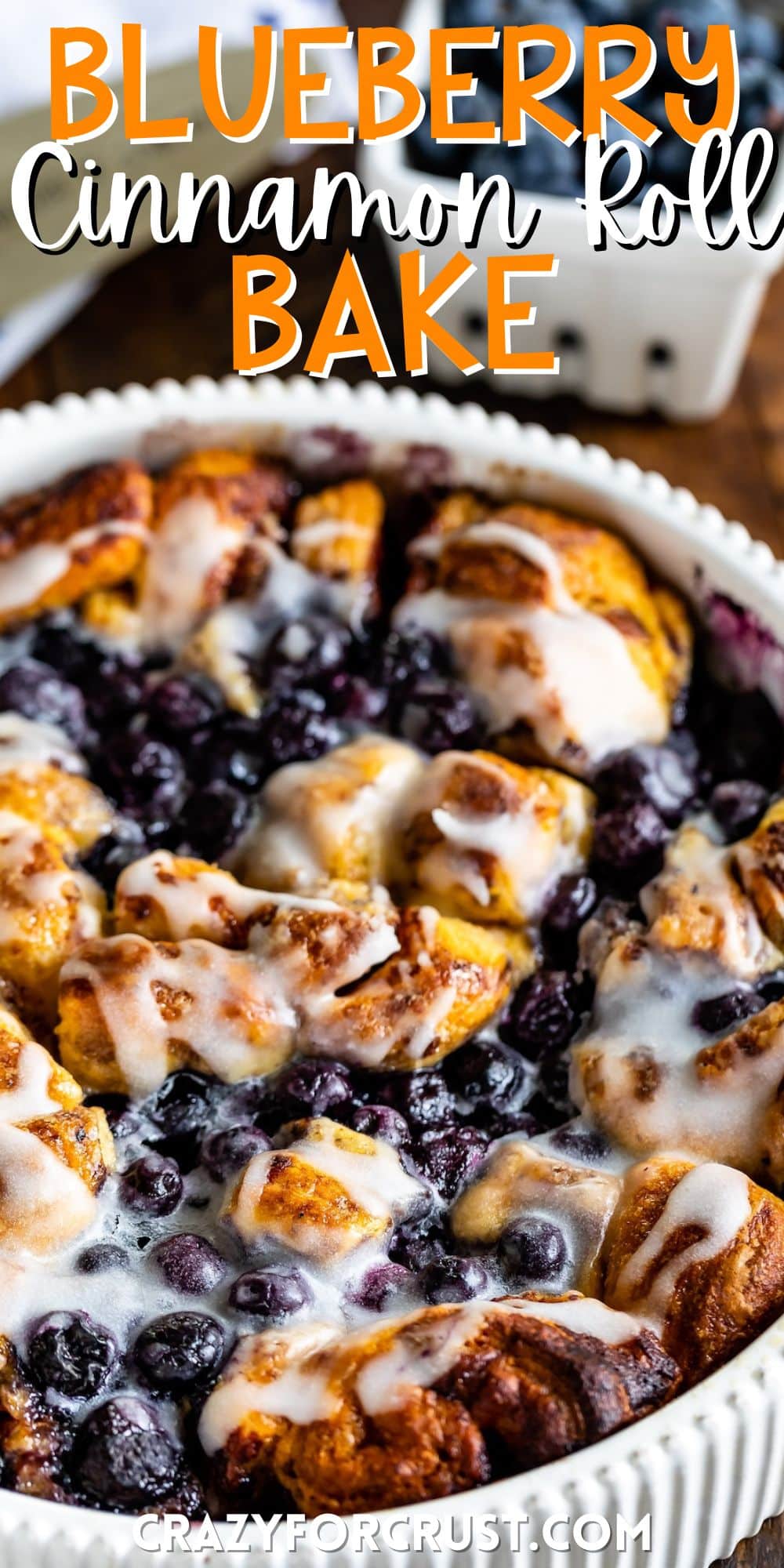 cinnamon roll bake with blueberries baked in a white pan with words on the image.