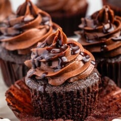 unwrapped cupcake with chocolate frosting and chocolate sauce drizzled over top.