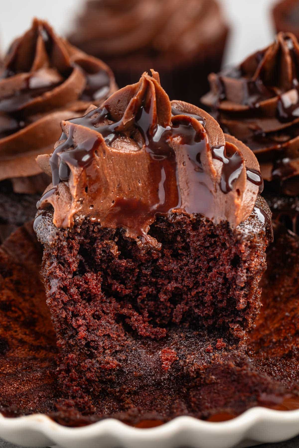 unwrapped cupcake with chocolate frosting and chocolate sauce drizzled over top.