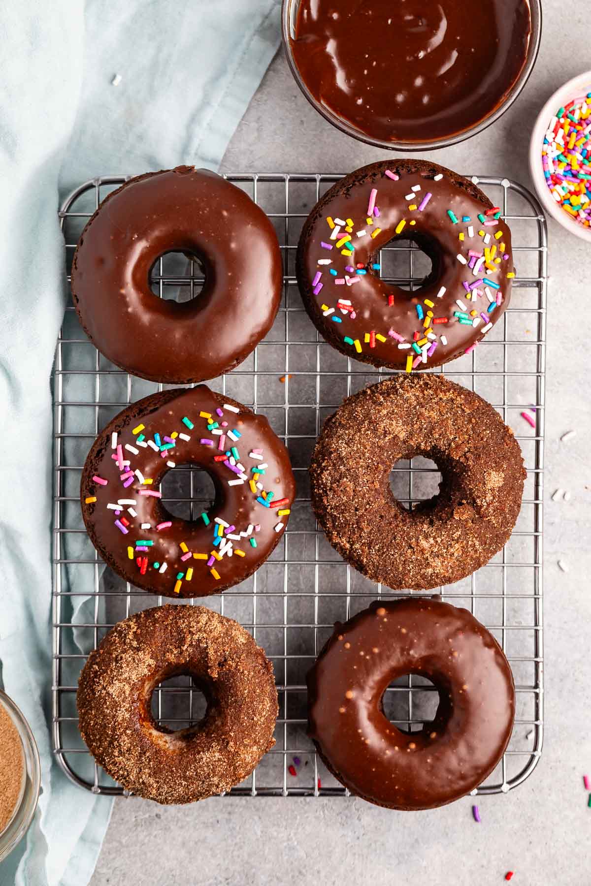 stacked chocolate donuts with chocolate glaze and colorful sprinkles and sugar on top,