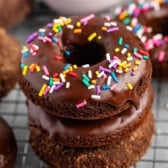 stacked chocolate donuts with chocolate glaze and colorful sprinkles on top,