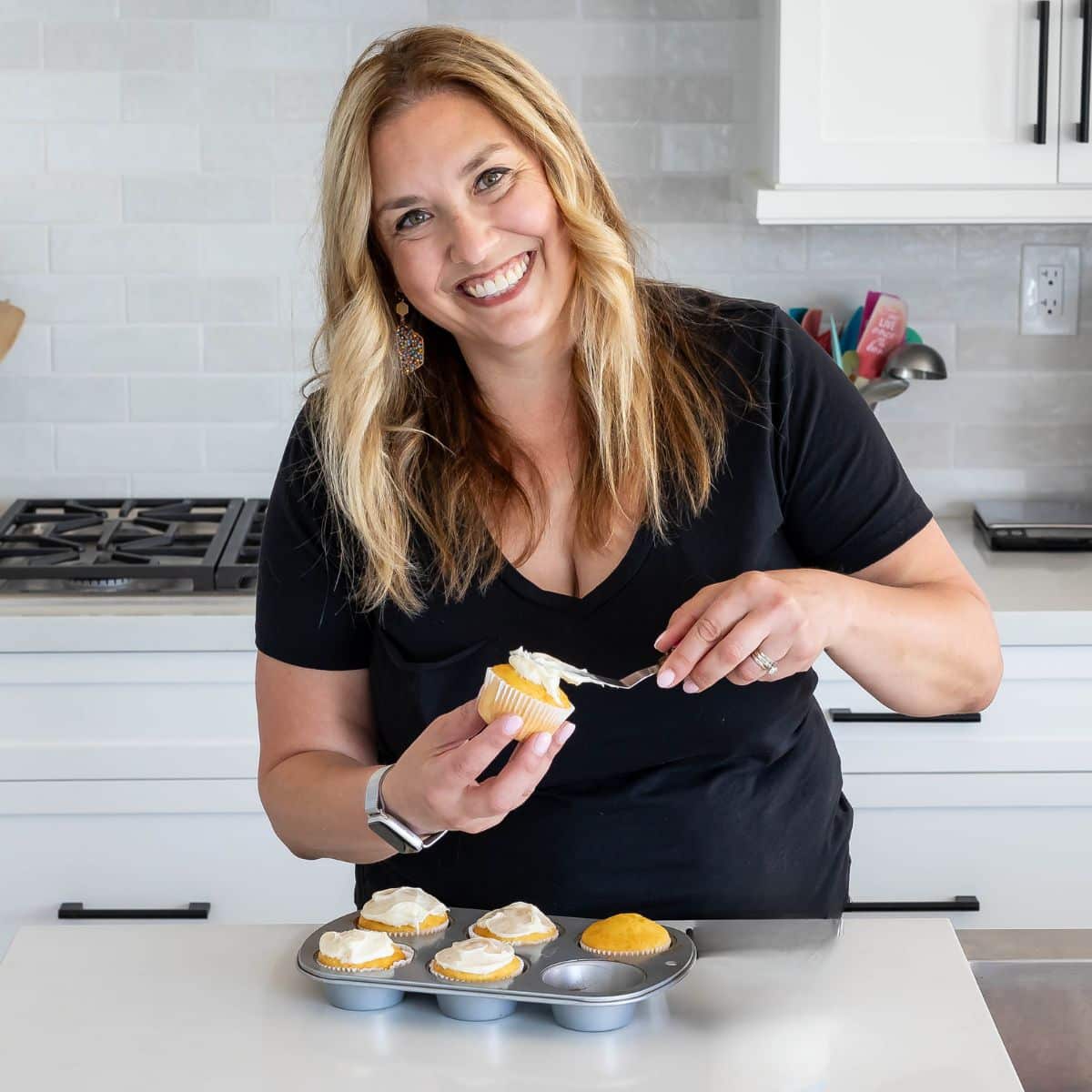 woman in kitchen frosting cupcakes