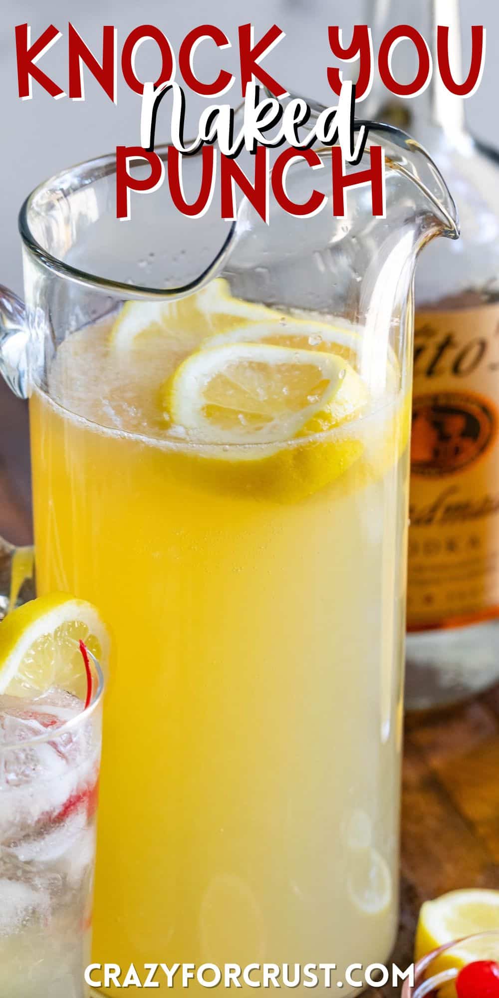 yellow party punch in a tall clear pitcher with lemon slices inside with words on the image.