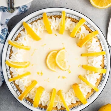 lemon pie in a tin with sliced lemons on top.