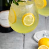 tall clear glass of yellow limoncello with sliced lemons throughout the drink.