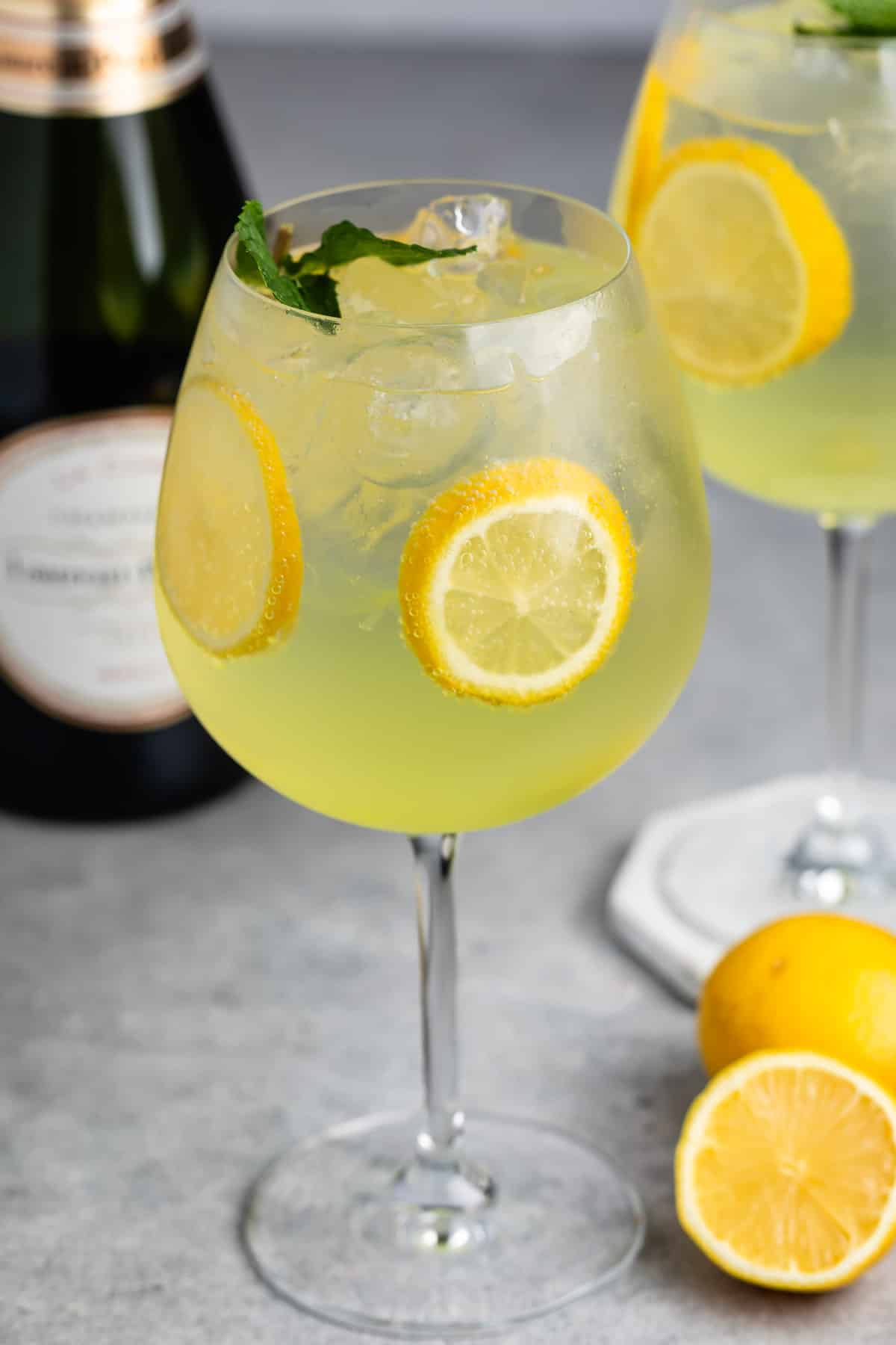 tall clear glass of yellow limoncello with sliced lemons throughout the drink.