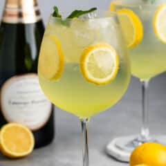 tall clear glass of yellow limoncello with sliced lemons throughout the drink.