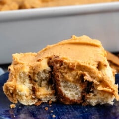 one cinnamon roll covered in peanut butter on a blue plate.