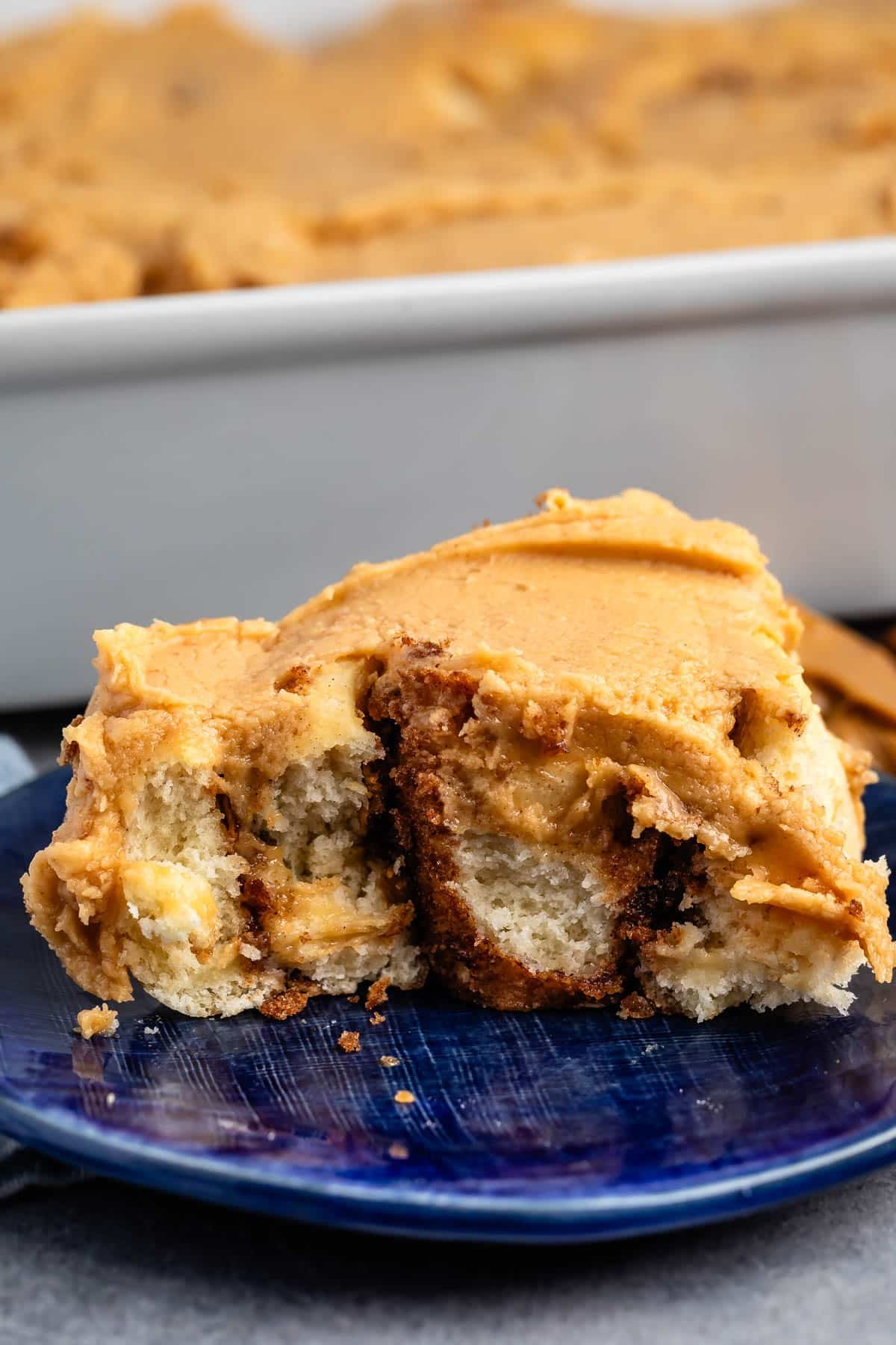 one cinnamon roll covered in peanut butter on a blue plate.