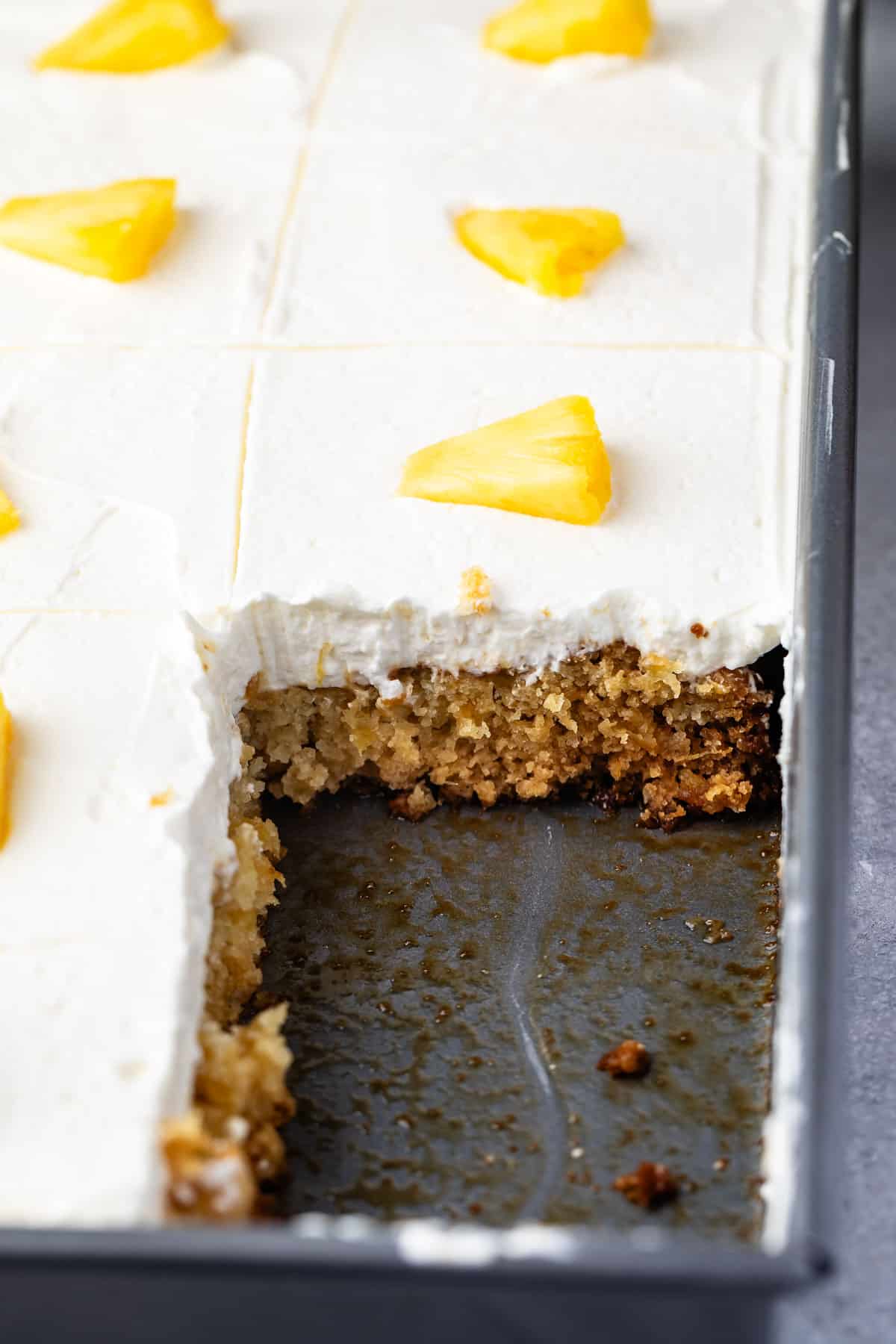 pineapple cake with white frosting on top and with a sliced pineapple.