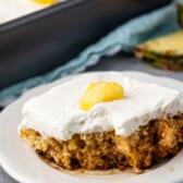 pineapple cake with white frosting on top and with a sliced pineapple.