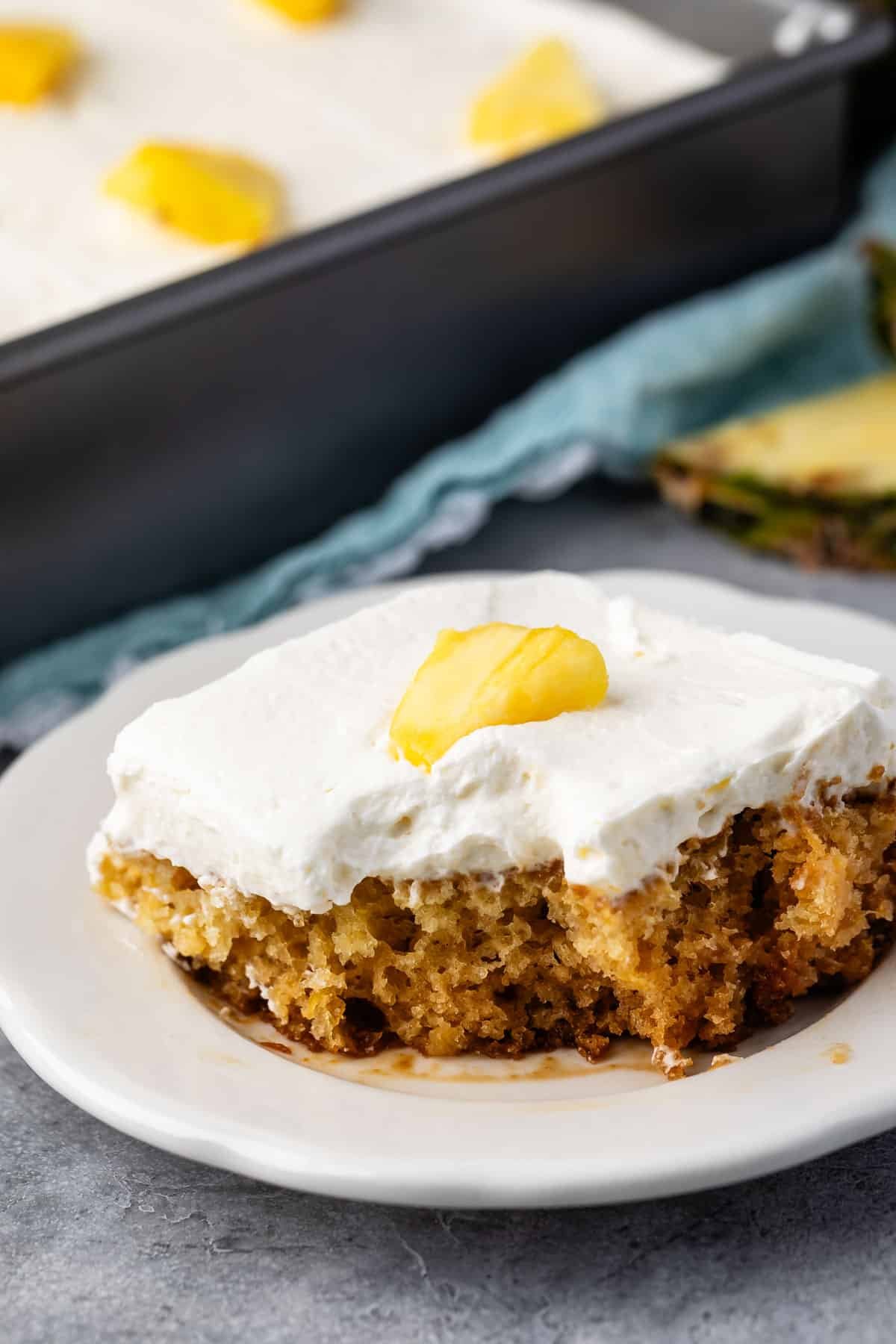 pineapple cake with white frosting on top and with a sliced pineapple.