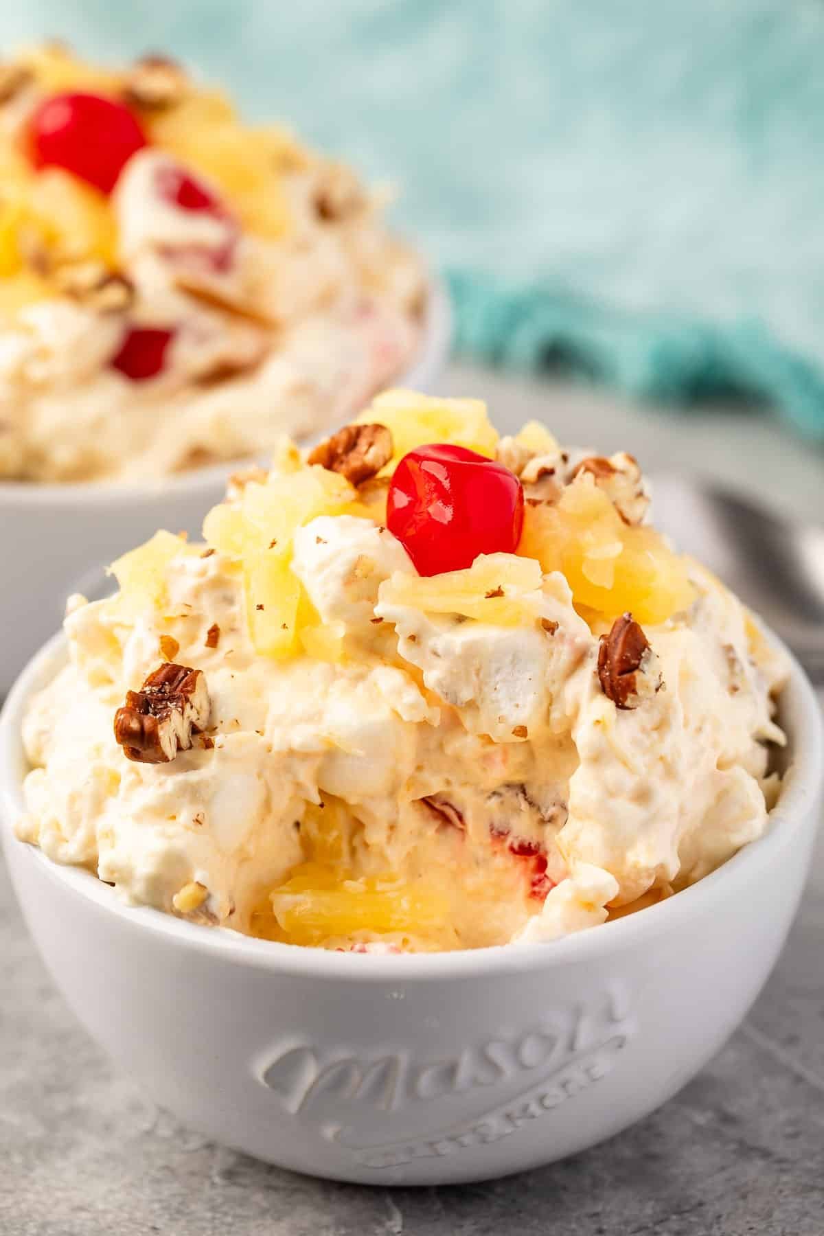 pineapple fluff with nuts and cherries on top in a white bowl.