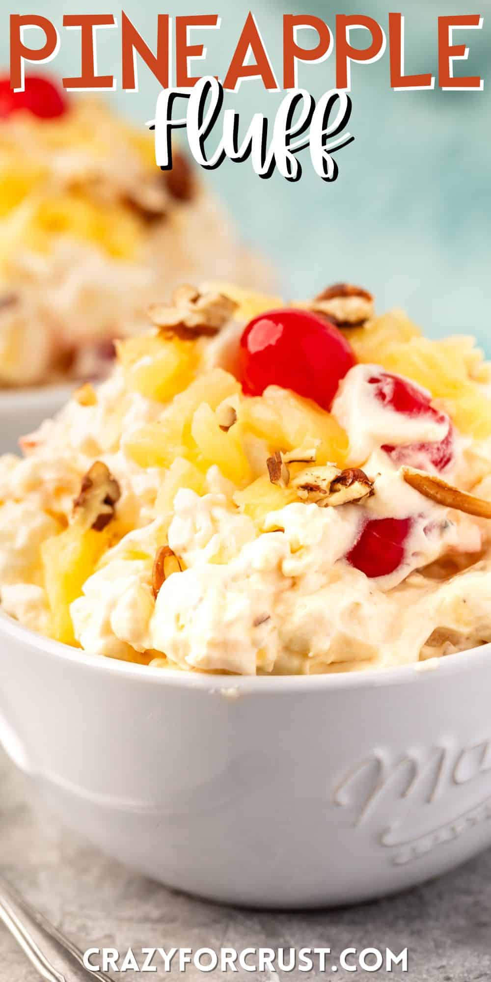 pineapple fluff with nuts and cherries on top in a white bowl with words on the image.