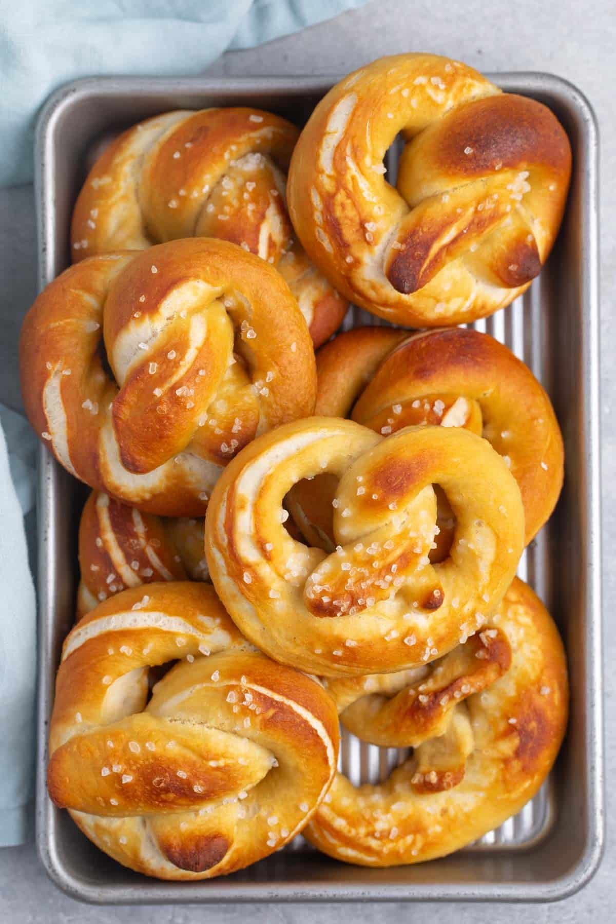 golden brown soft pretzels stacked with salt on top.