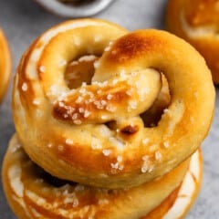 golden brown soft pretzels stacked with salt on top.