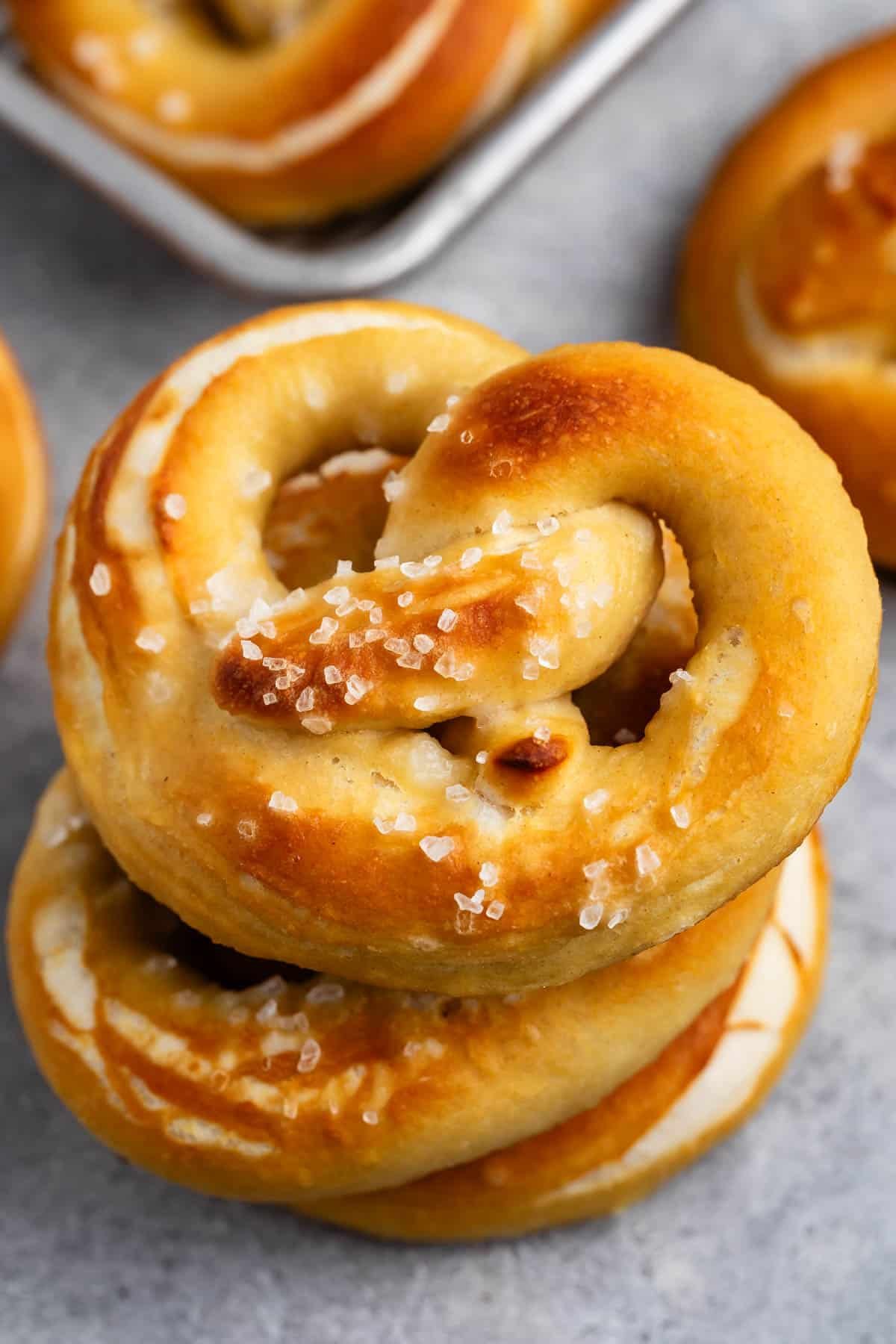 golden brown soft pretzels stacked with salt on top.