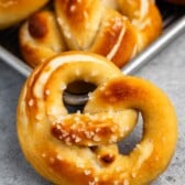 golden brown soft pretzels stacked with salt on top.