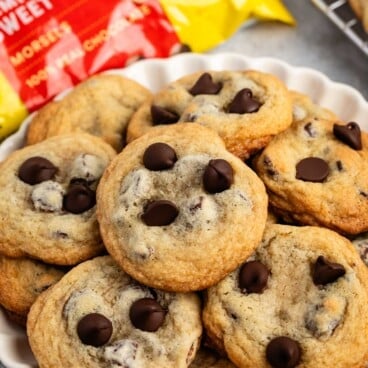 A stack of soft and chewy Toll House cookies on a white plate.