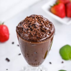 chocolate mousse in a tall clear glass with chocolate shavings on top.