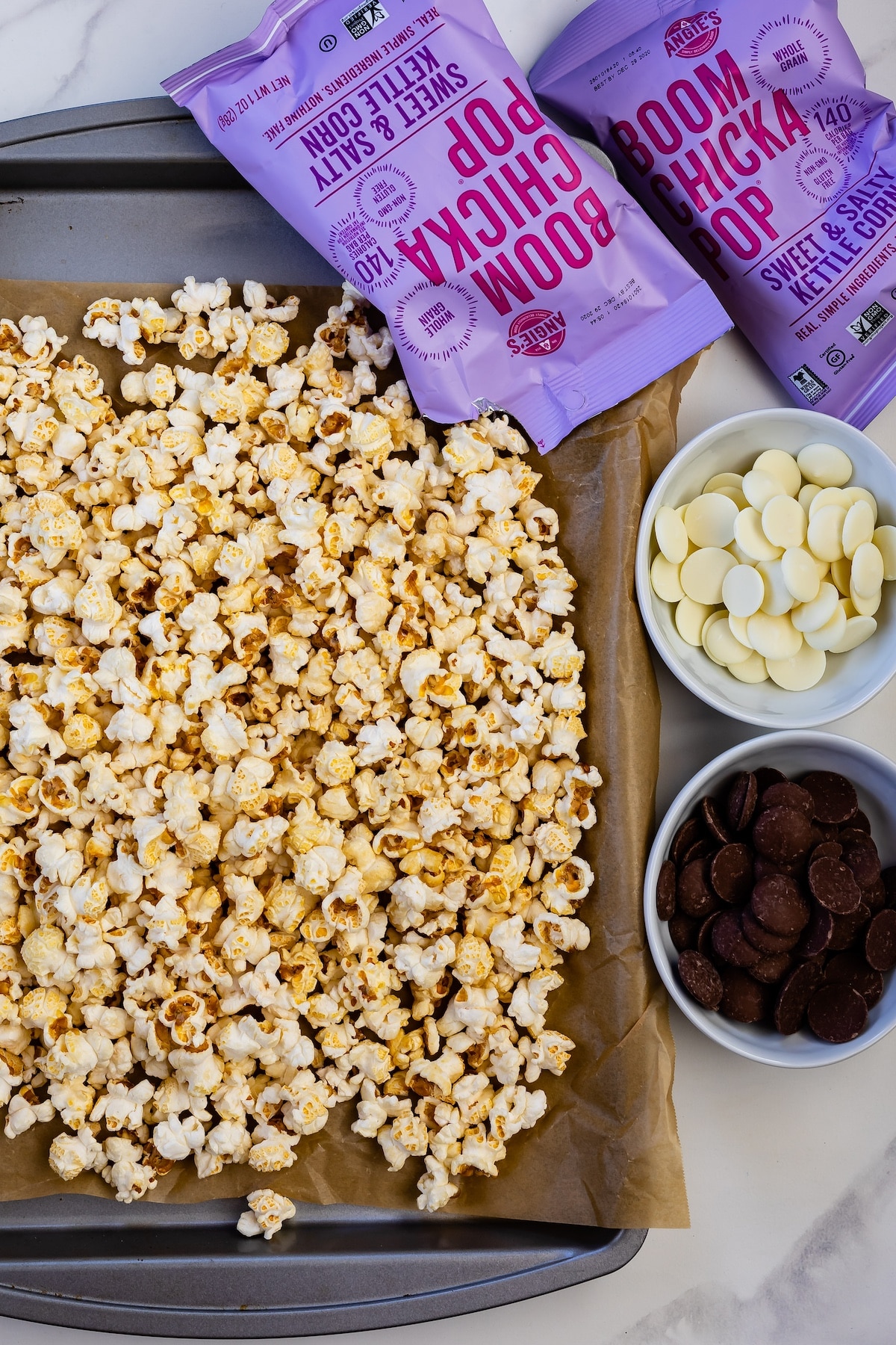 popcorn on a baking sheet next to popcorn bags and chocolate melts.