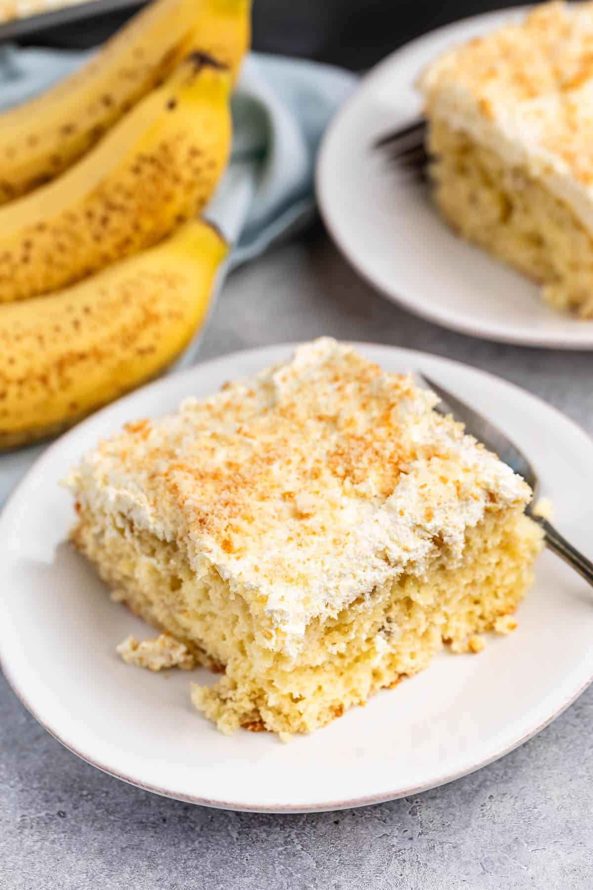 square slice of cake on a white plate next to a fork.