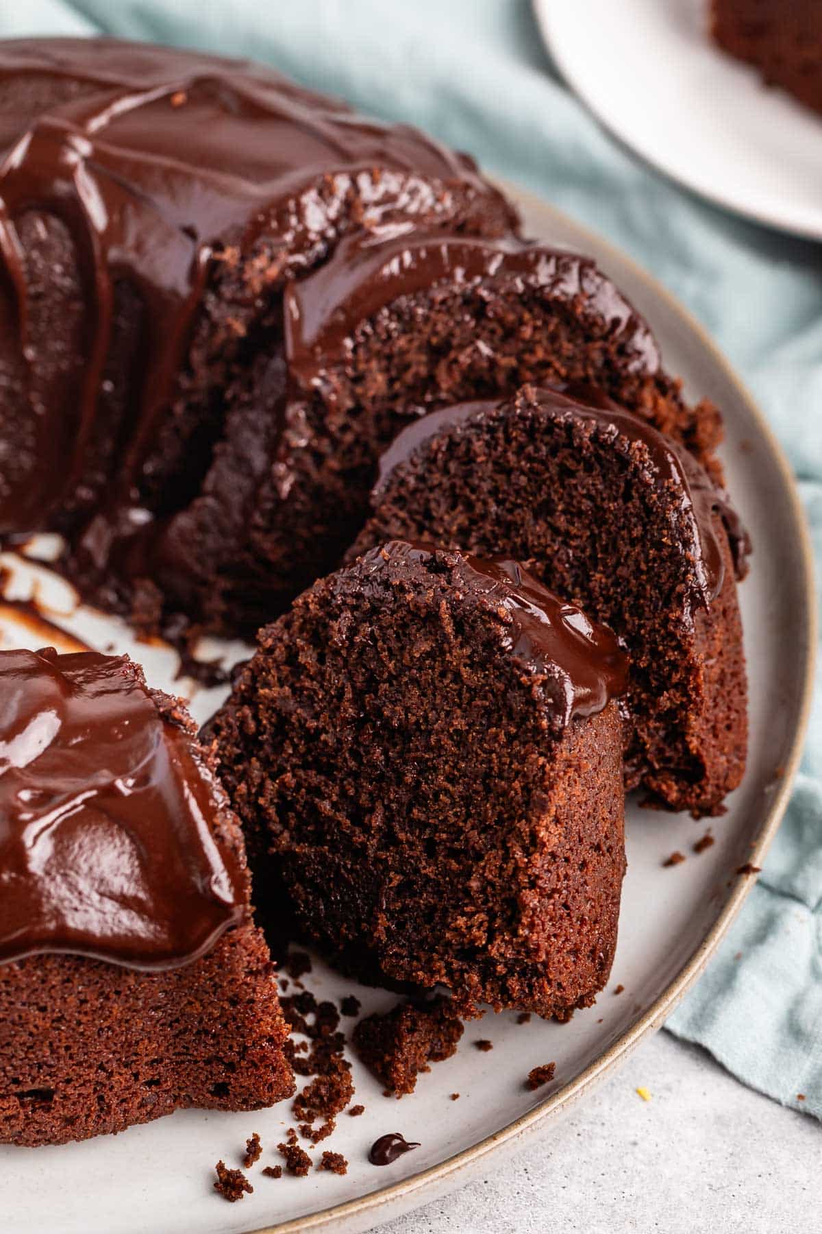 slice of chocolate cake on a white plate with a chocolate glaze on top.