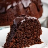 slice of chocolate cake on a white plate with a chocolate glaze on top.