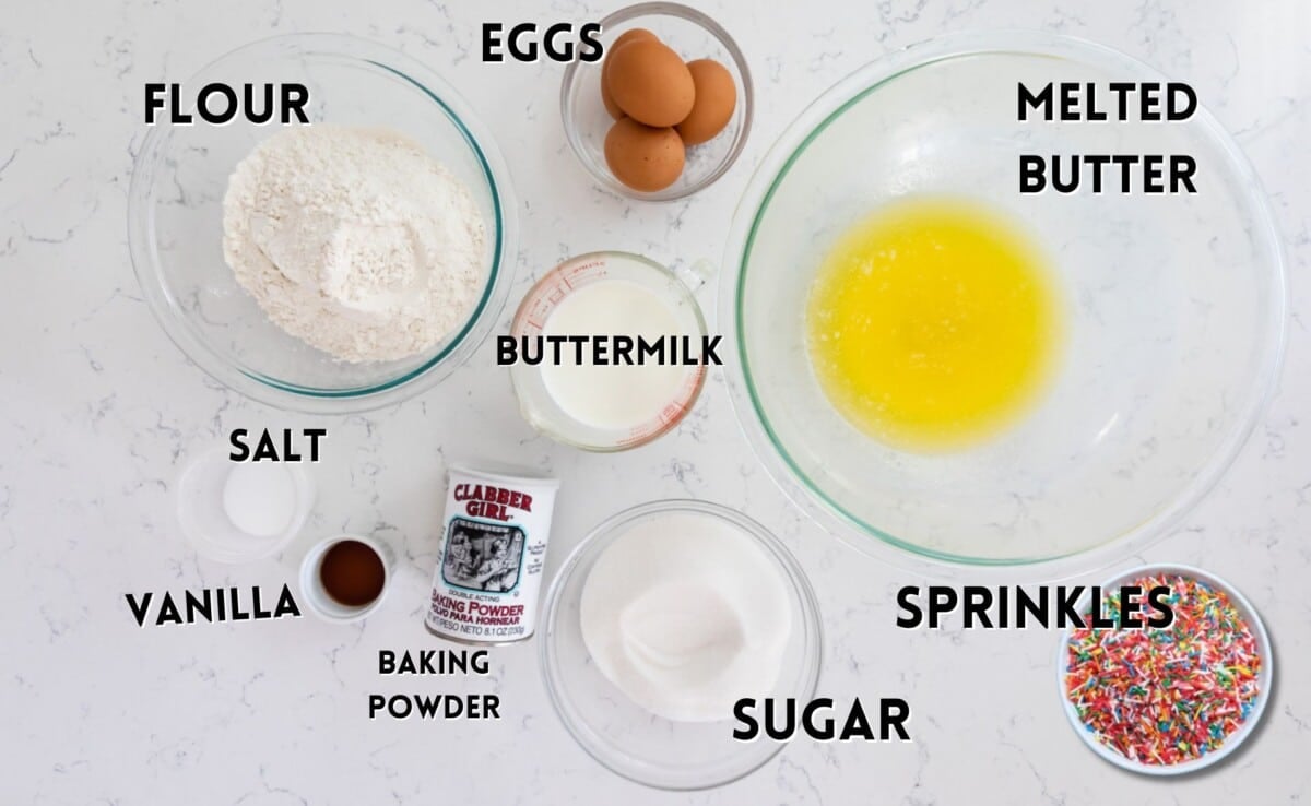 ingredients in funfetti cake laid out on a white marble counter.