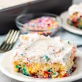 white cake with colorful sprinkles baked in and white frosting with more sprinkles mixed in on top.