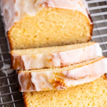 sliced lemon bread with a glaze on top on a drying rack.