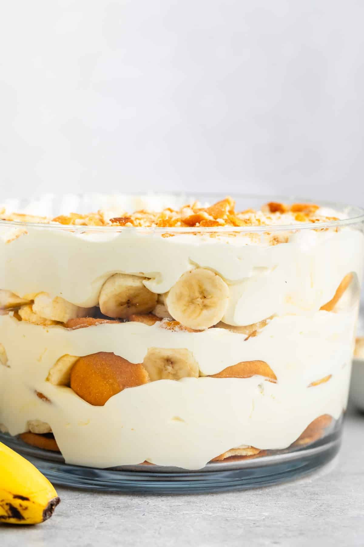 banana pudding in a clear glass tub with sliced bananas and cream inside.