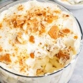 banana pudding in a clear glass tub with sliced bananas and cream inside.
