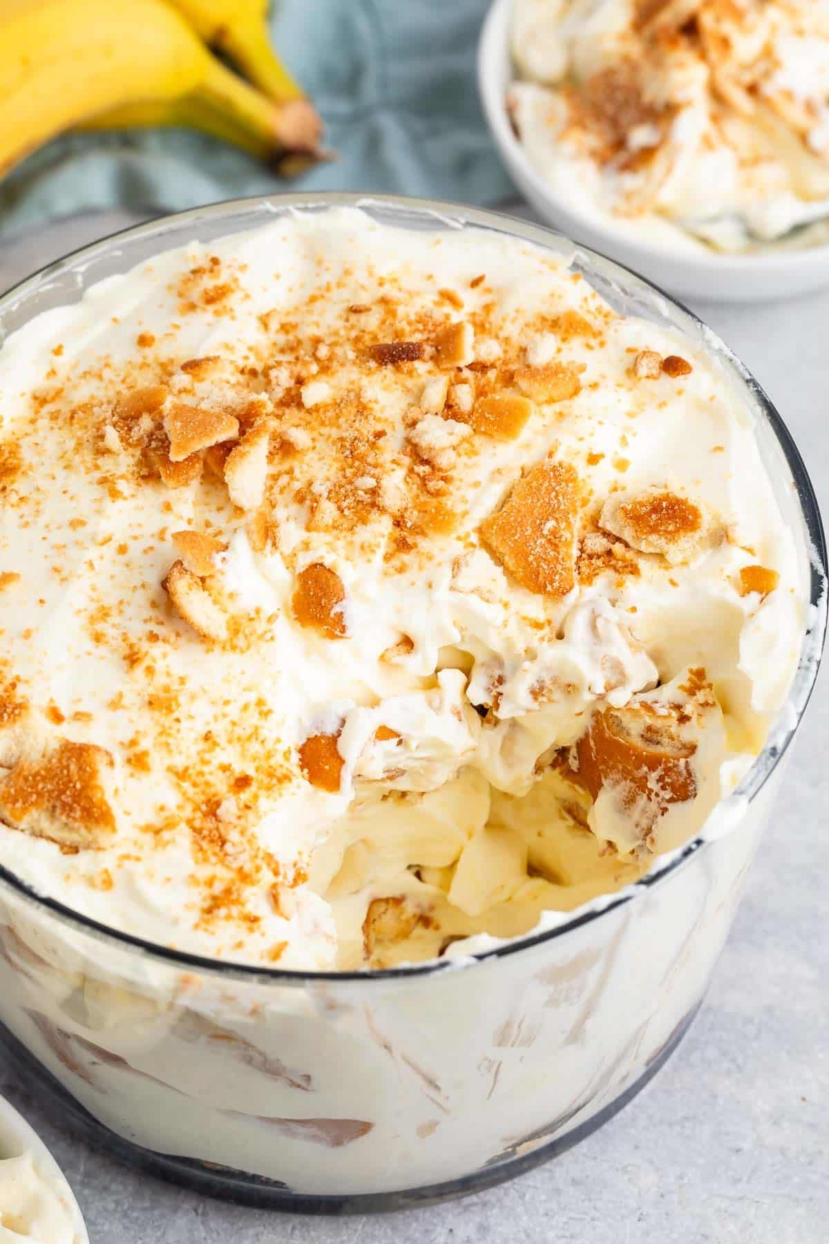 banana pudding in a clear glass tub with sliced bananas and cream inside.