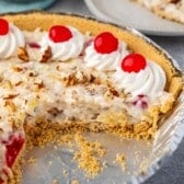 millionaire pie in a silver tin with pecans and cherries on top of the pie.