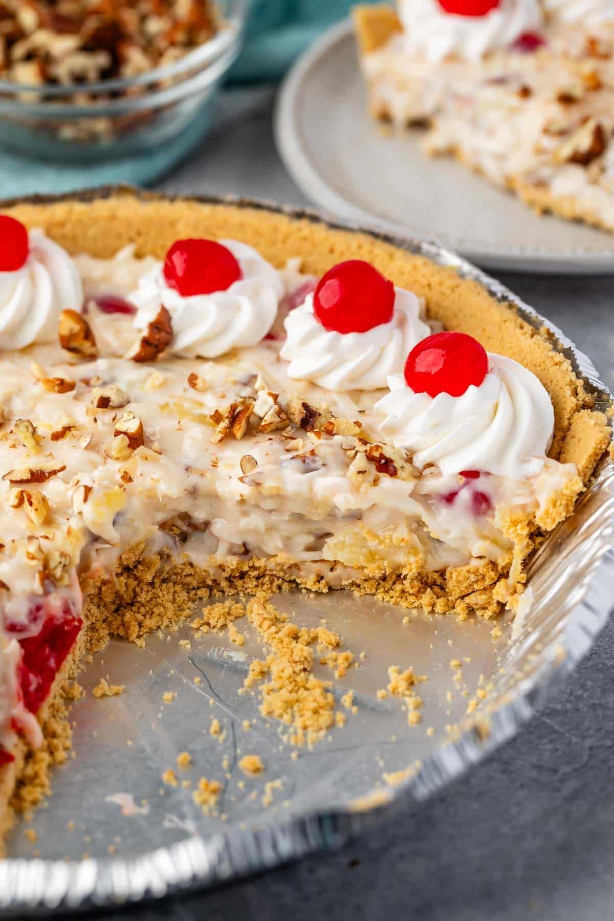 millionaire pie in a silver tin with pecans and cherries on top of the pie.