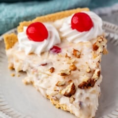 slice of millionaire pie on a grey plate with pecans and cherries on top.