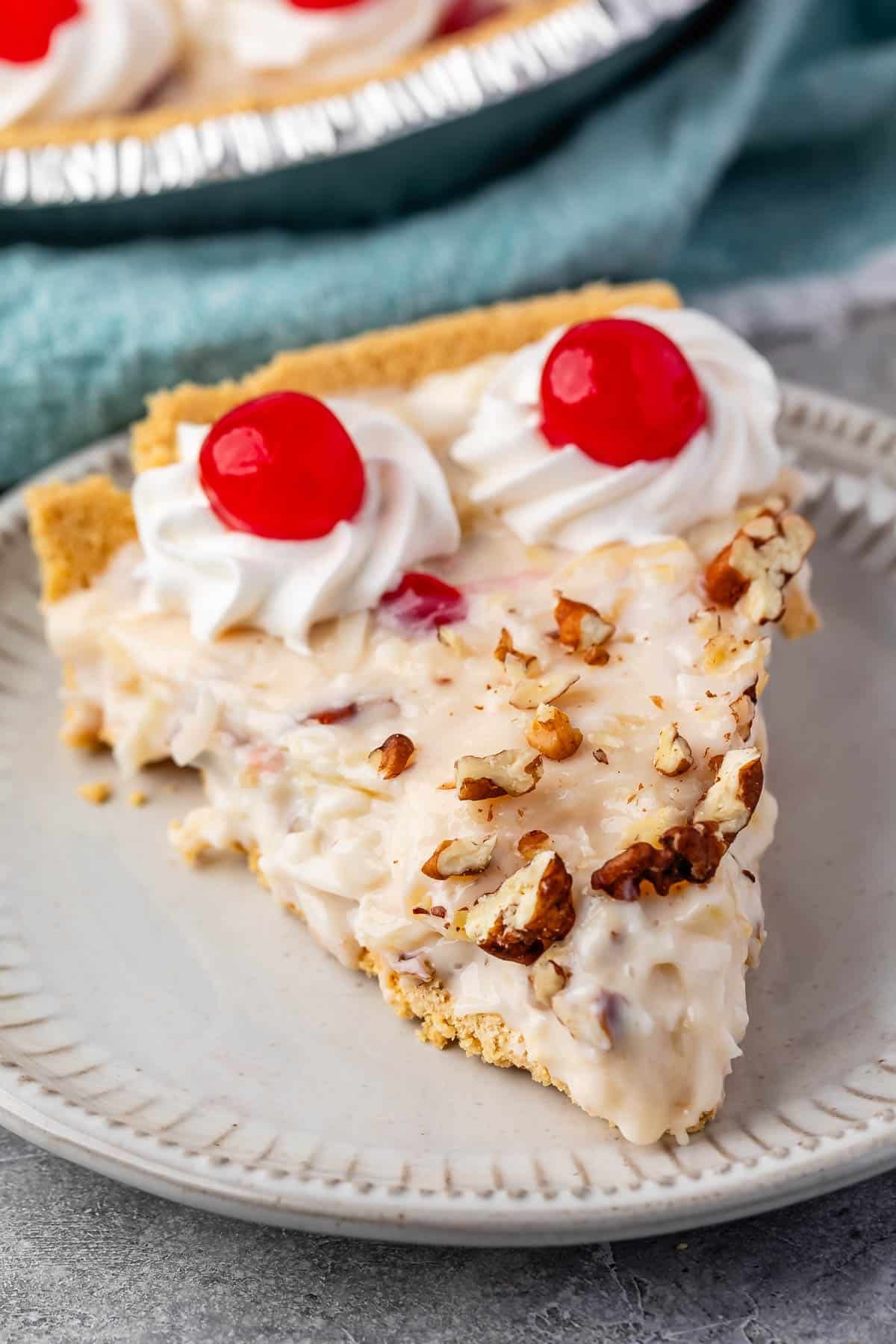 slice of millionaire pie on a grey plate with pecans and cherries on top.