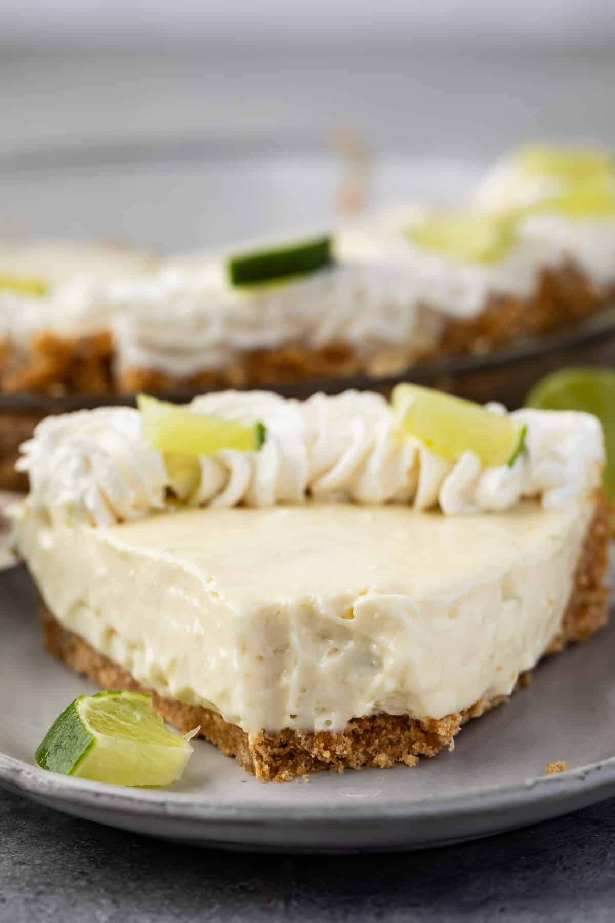 slice of key lime pie with whipped cream and sliced lime on top.