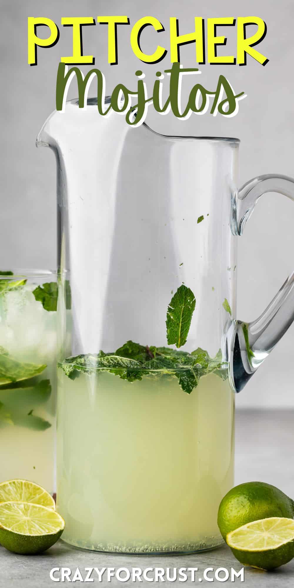 mojito in a tall clear pitcher with sliced limes in and around the glass with mint with words on the image.
