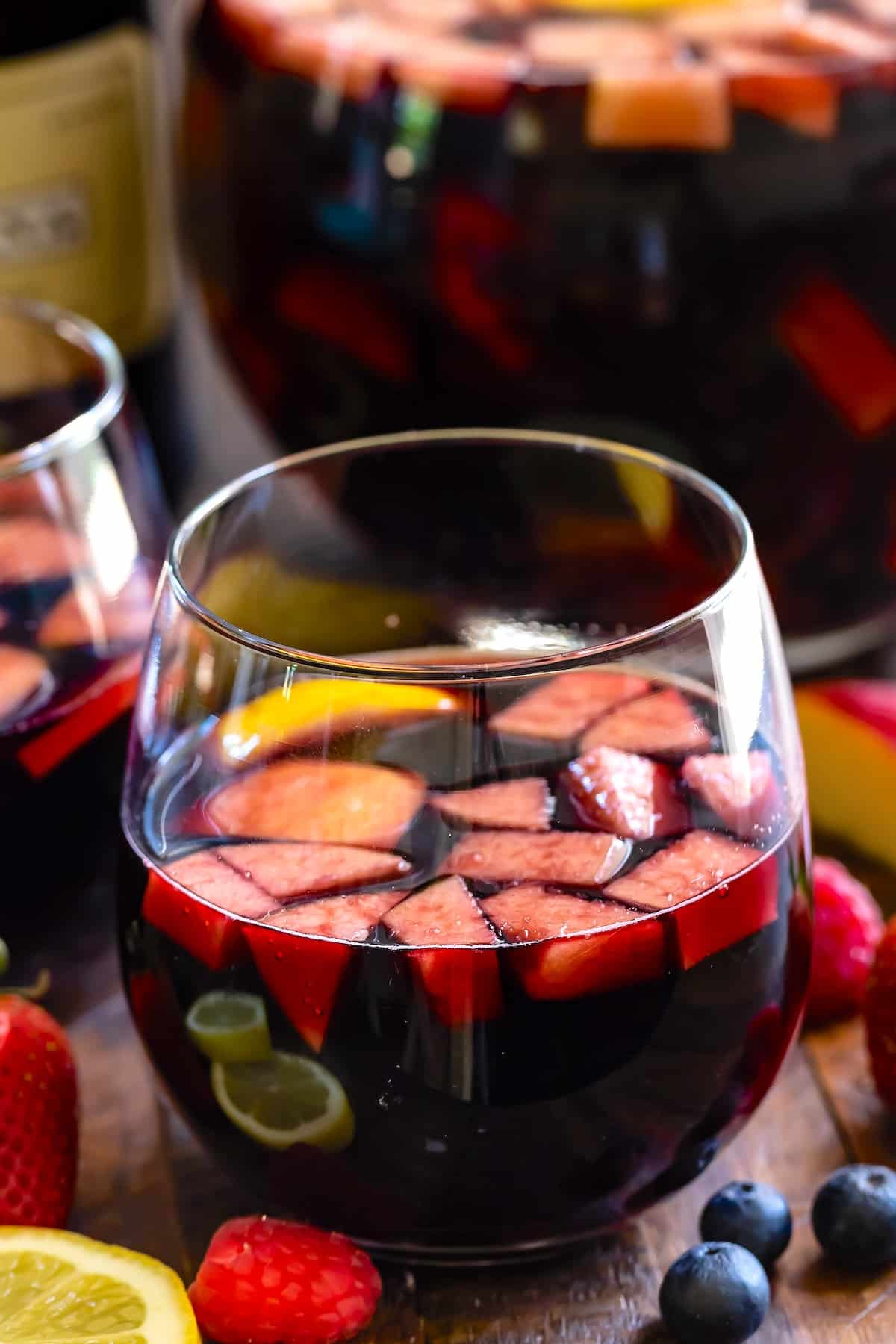 dark red wine in a short clear glass with fruit chopped up inside.