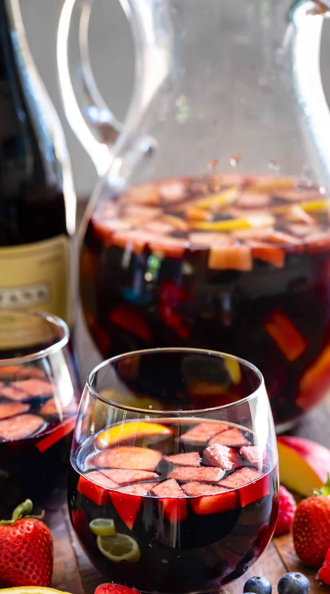 dark red wine in a short clear glass with fruit chopped up inside.