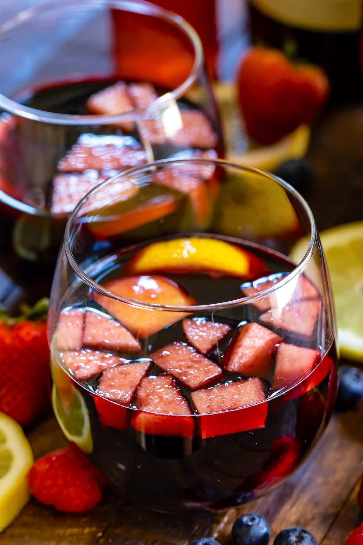 dark red wine in a short clear glass with fruit chopped up inside.