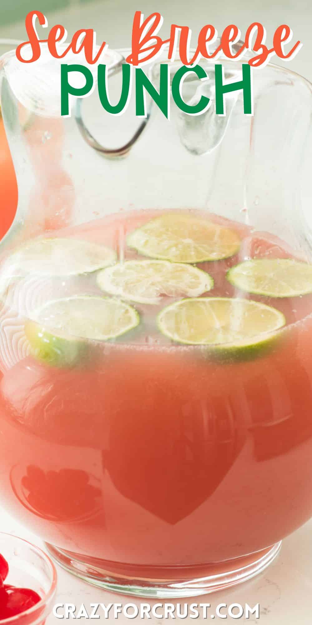 pink drink in a clear big pitcher with sliced limes inside with words on the image.
