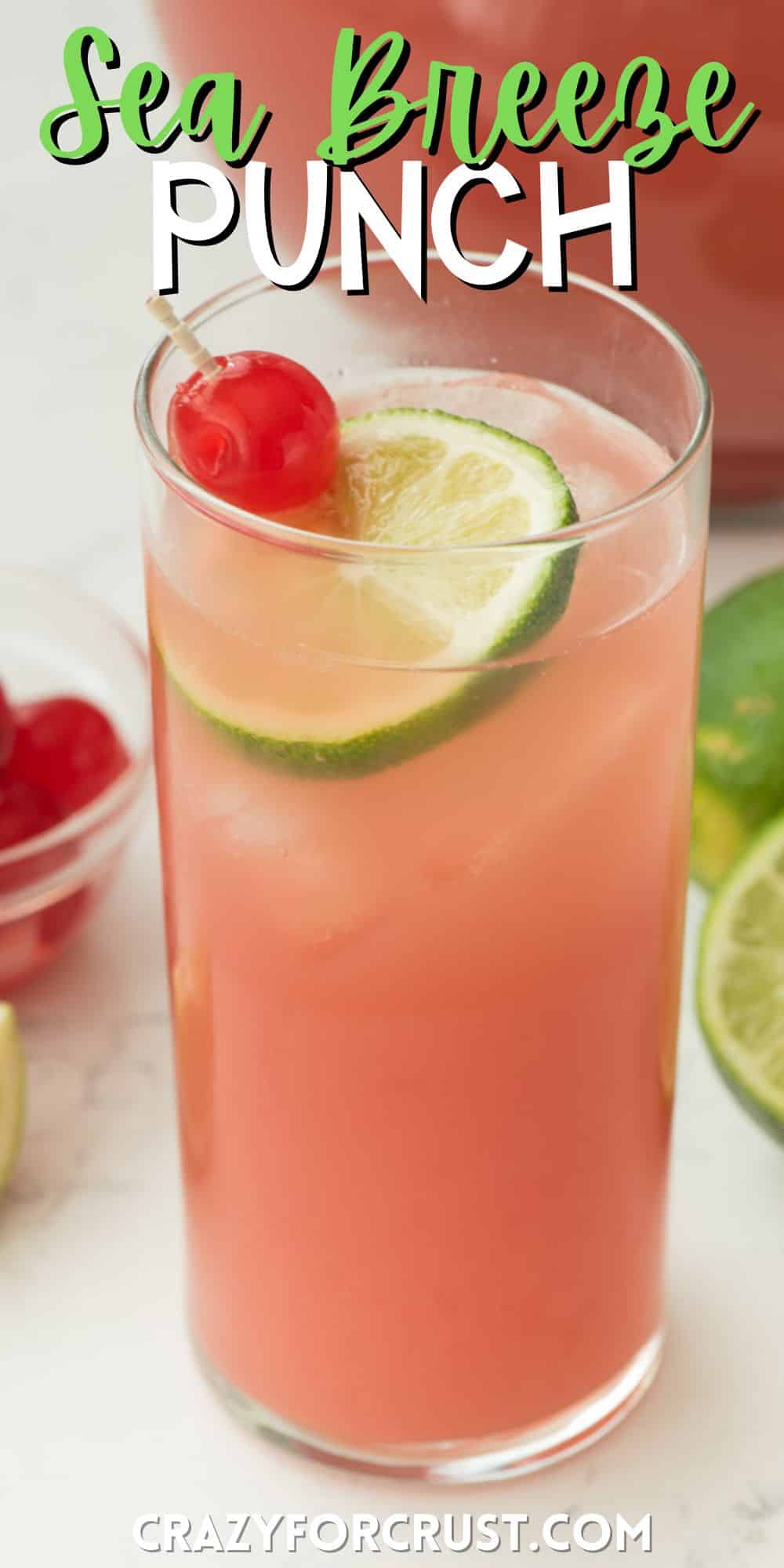 pink drink in a tall clear glass with a lime and a cherry inside with words on the image.