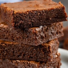stacked brownies on a white plate.