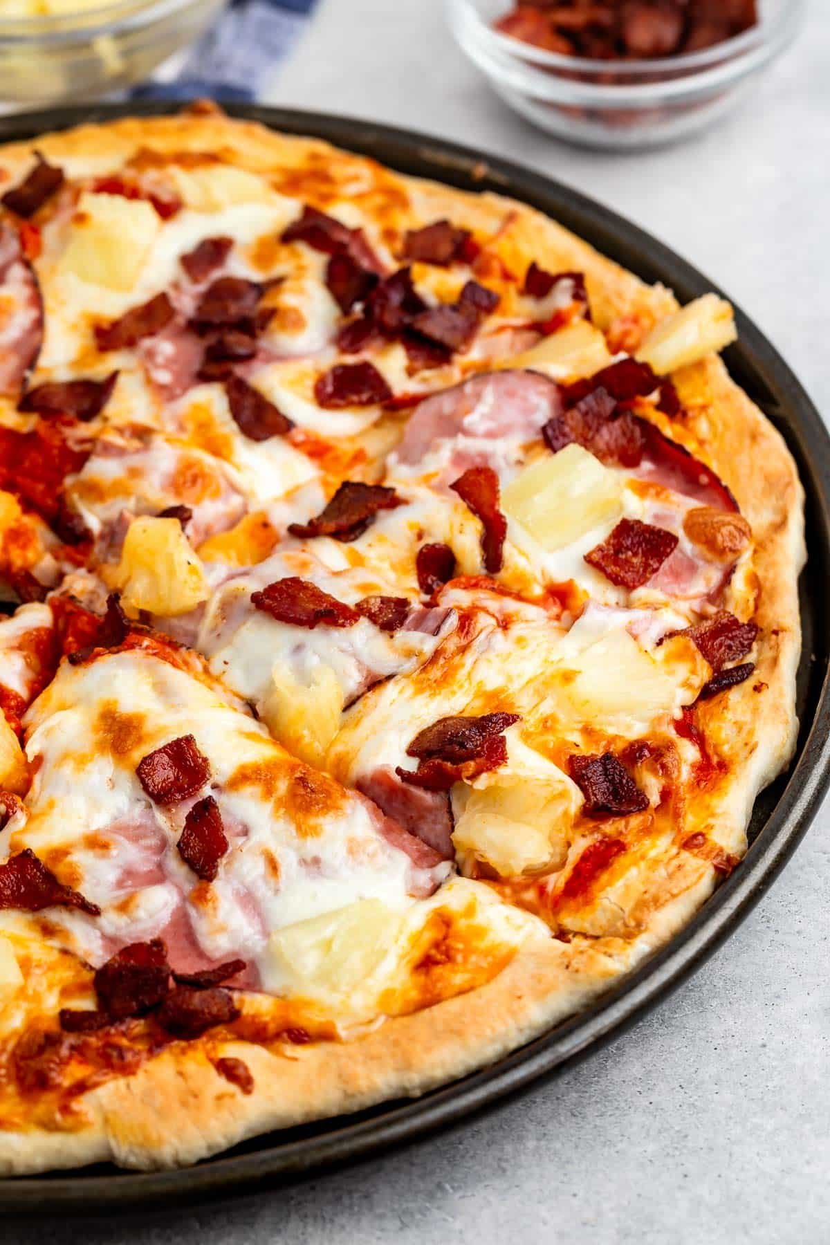 pizza with cheese, pineapple, ham, and bacon on top.