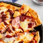 pizza with cheese, pineapple, ham, and bacon on top.