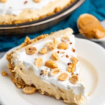 peanut butter pie on a white plate with peanuts on top.